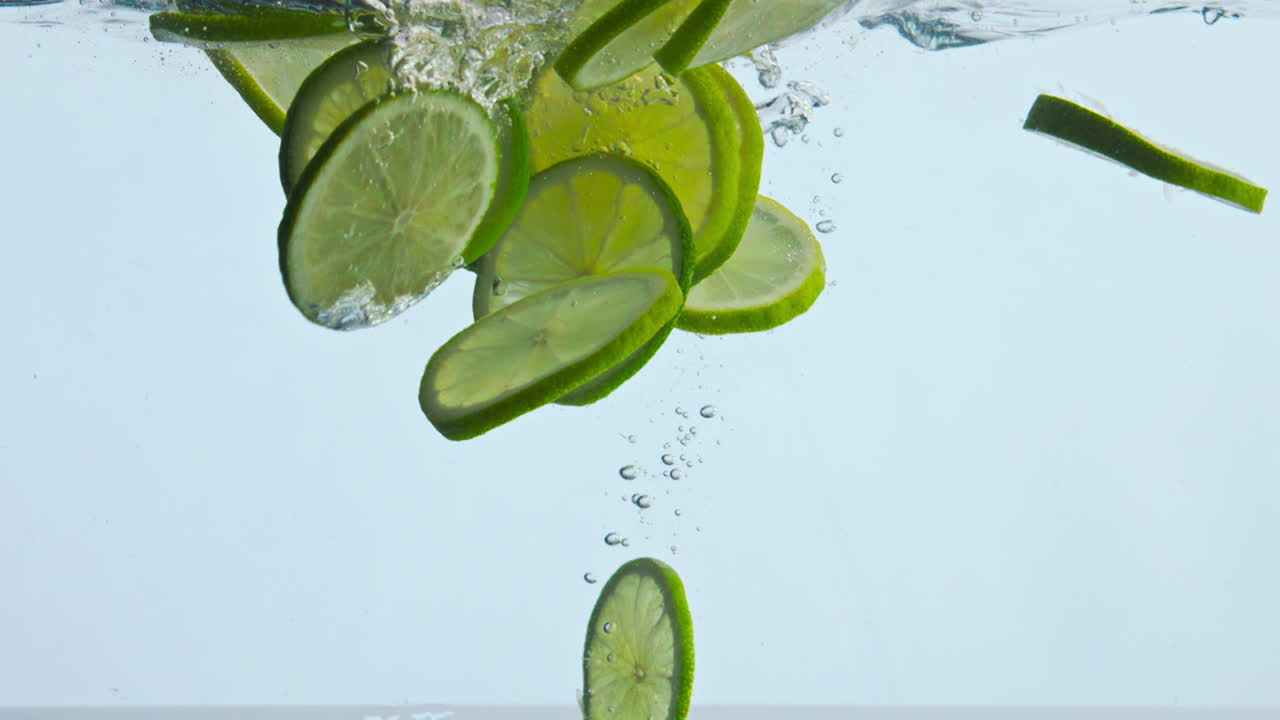 agua de cal agria cortada flotando sobre un fondo blanco de cerca. cítricos bajo el agua.