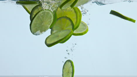 Agua-De-Lima-Agria-En-Rodajas-Flotando-Sobre-Fondo-Blanco-De-Cerca.-Cítricos-Bajo-El-Agua.