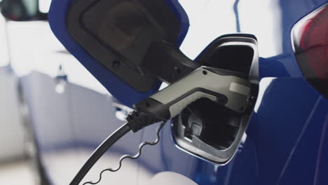 primer plano de una mujer que desprende el cable de carga de un coche eléctrico ecológico de cero emisiones