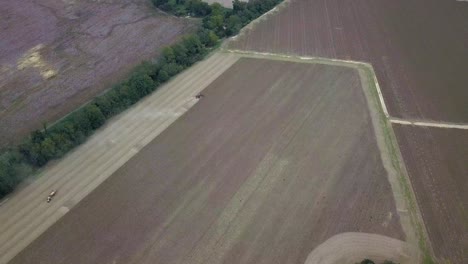 Große-Luftaufnahmen-Von-Traktoren,-Die-Auf-Staubigen-Feldern-Auf-Dem-Bauernhof-Arbeiten