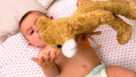 bebé tendido en la cuna chupando un chupete sosteniendo un peluche