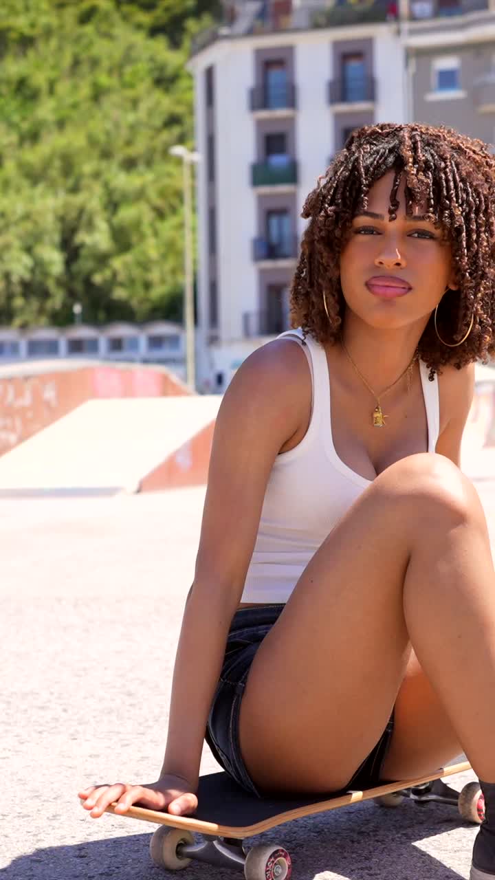 Donna seduta su uno skateboard in un ambiente urbano