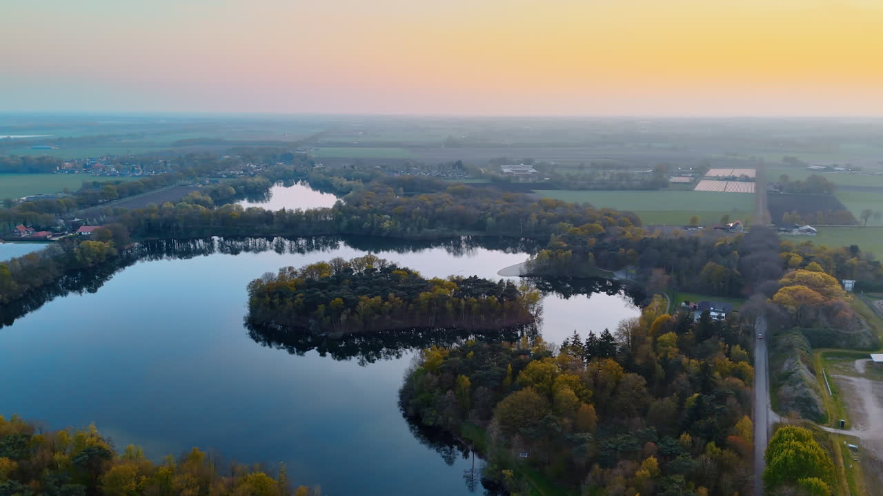 Beautiful sunset over Dutch lakes. An aerial view captures serene lakes and vibrant trees at sunset, showcasing the Netherlands natural beauty