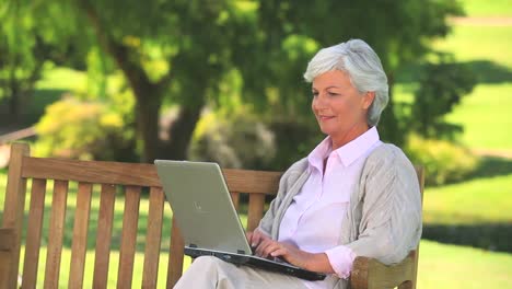 Reife-Frau,-Die-Draußen-Auf-Ihrem-Laptop-Surft