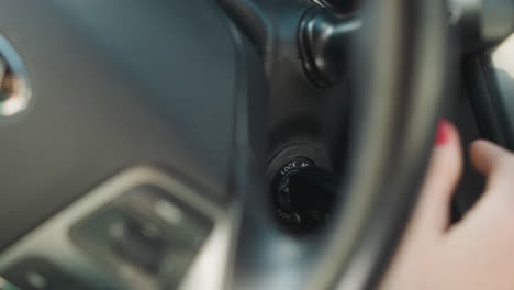 female hand turns on ignition key to crank engine of car