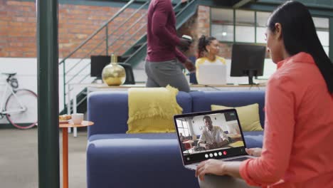 Mujer-Birracial-Usando-Una-Computadora-Portátil-Para-Videollamada,-Con-Un-Colega-De-Negocios-En-La-Pantalla