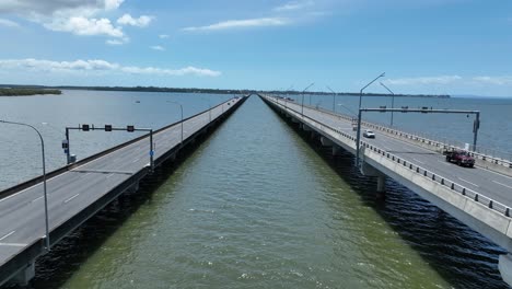 Drone-establishing-push-in-shot-of-Ted-Smout-Memorial-Bridge,-camera-flying-in-between-both-bridge-lanes,-following-cars-as-they-drive-across-the-bridge