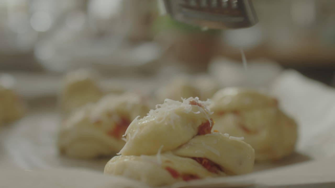 Grating cheese onto unbaked pastries