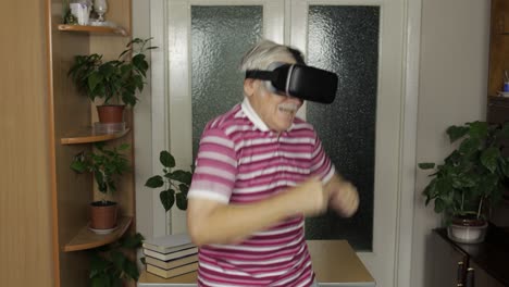 Senior-grandfather-in-virtual-headset-glasses-watching-video-in-3D-vr-helmet-and-dancing,-having-fun