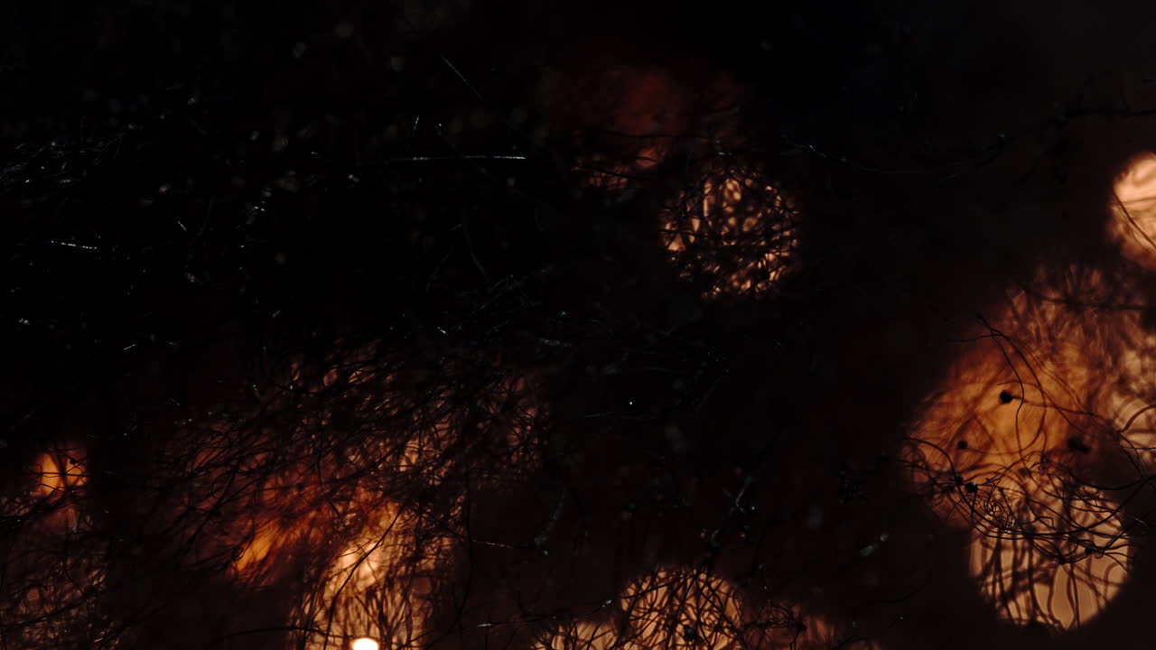 Flames burning through textured surface in a macro shot, creating intense glow and .movement