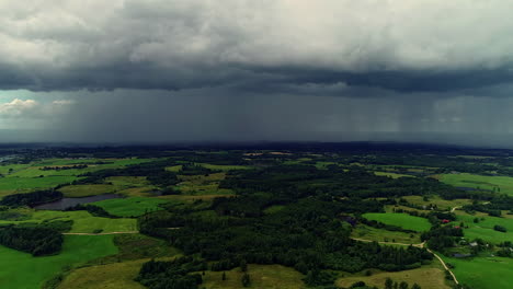 Luftüberflug-Ländliche-Landschaft-Mit-Grünen-Feldern-Und-Wald-Bei-Stürmischem-Regenhimmel-Mit-Dichten-Wolken-Im-Hintergrund