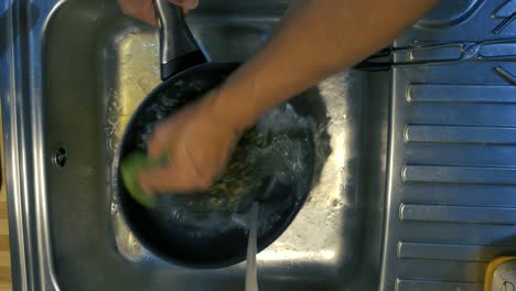 overhead shot of man´s arms scrubbing  a pan