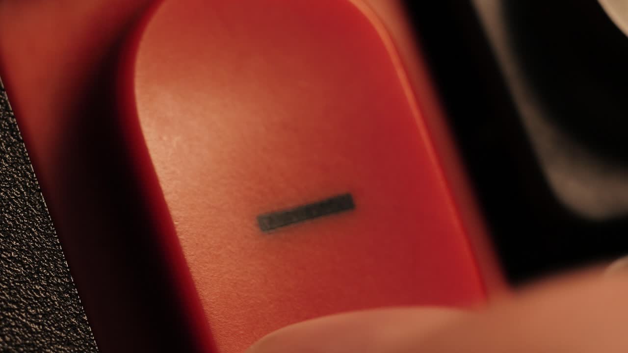 Close up of a finger pressing a red minus button in low light