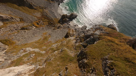 FPV-dive-of-an-impressive-cliff-overhanging-the-crashing-waves-of-the-sea,-Ryten-Hike-Lofoten-Islands-in-Norway,-impressive-low-flight