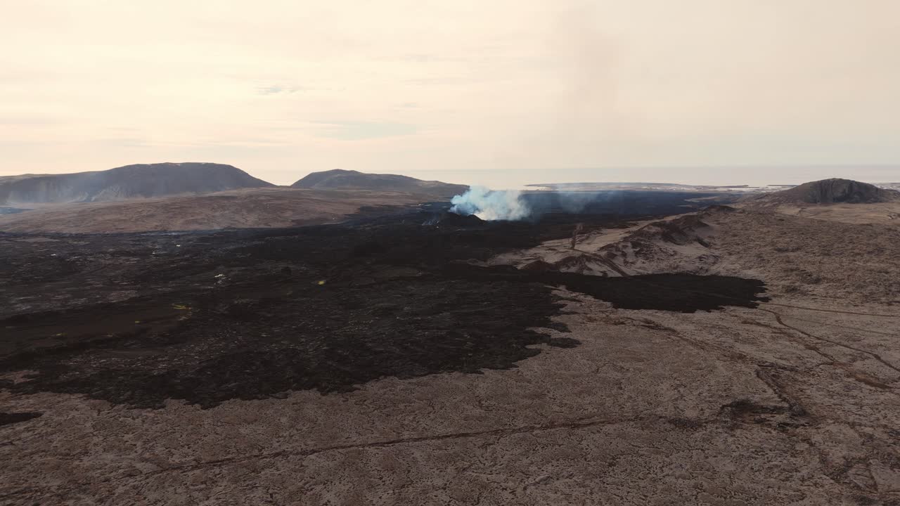 desierto volcánico desolado con volcán humeante y rocas ígneas
