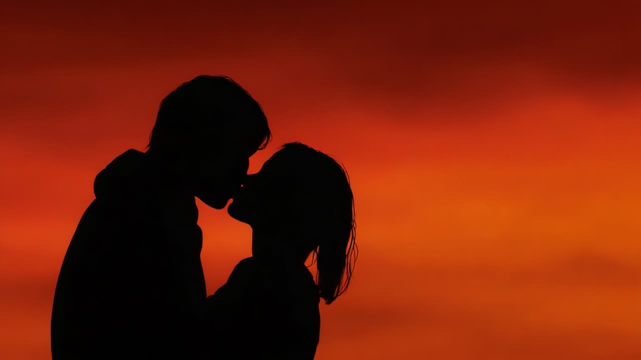 A Romantic Silhouette: A Couple Embracing as the Warm Hues of Sunset Illuminate Their Affectionate Moment Against a Dramatic Sky