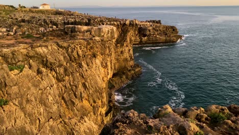 El-Sol-Se-Pone-Sobre-Los-Escarpados-Acantilados-De-Boca-Do-Inferno-En-Cascais,-Arrojando-Un-Cálido-Resplandor-Sobre-Las-Rocas-Y-El-Océano-Debajo