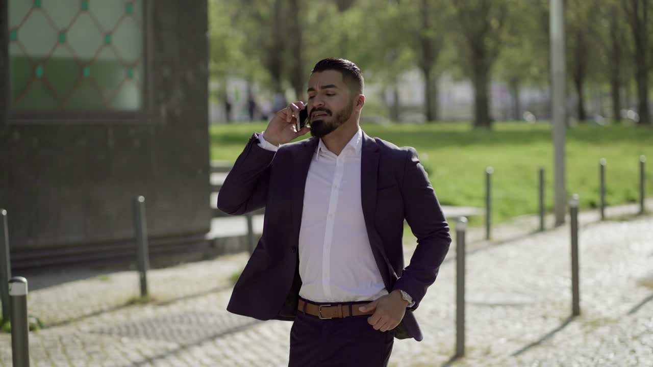 Uomo d'affari che parla allo smartphone e corre all'aperto