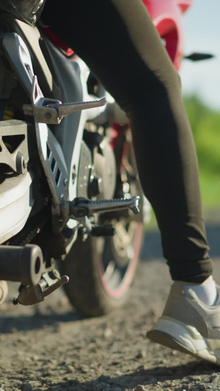 primer plano de un motociclista arrancando su motocicleta en la carretera, con un coche en la distancia acercándose en la dirección opuesta