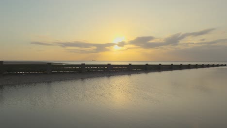 Calm-water-boat-on-horizon-with-sea-bird-flying-in-slow-motion-during-sunset-at-Fleetwood,-Lancashire,-UK