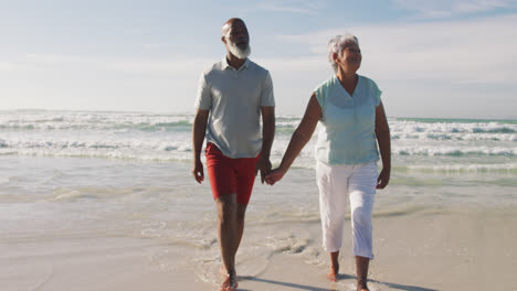 Pareja-Afroamericana-De-Alto-Rango-Caminando-Y-Tomándose-De-La-Mano-En-La-Playa