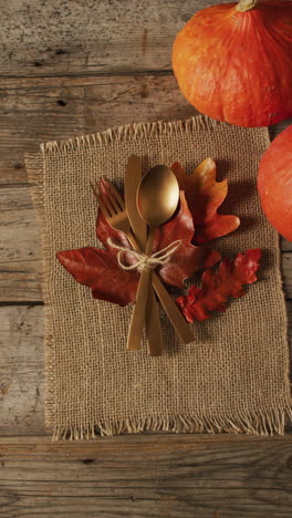 vídeo vertical de cubiertos, tela y calabaza sobre una superficie de madera