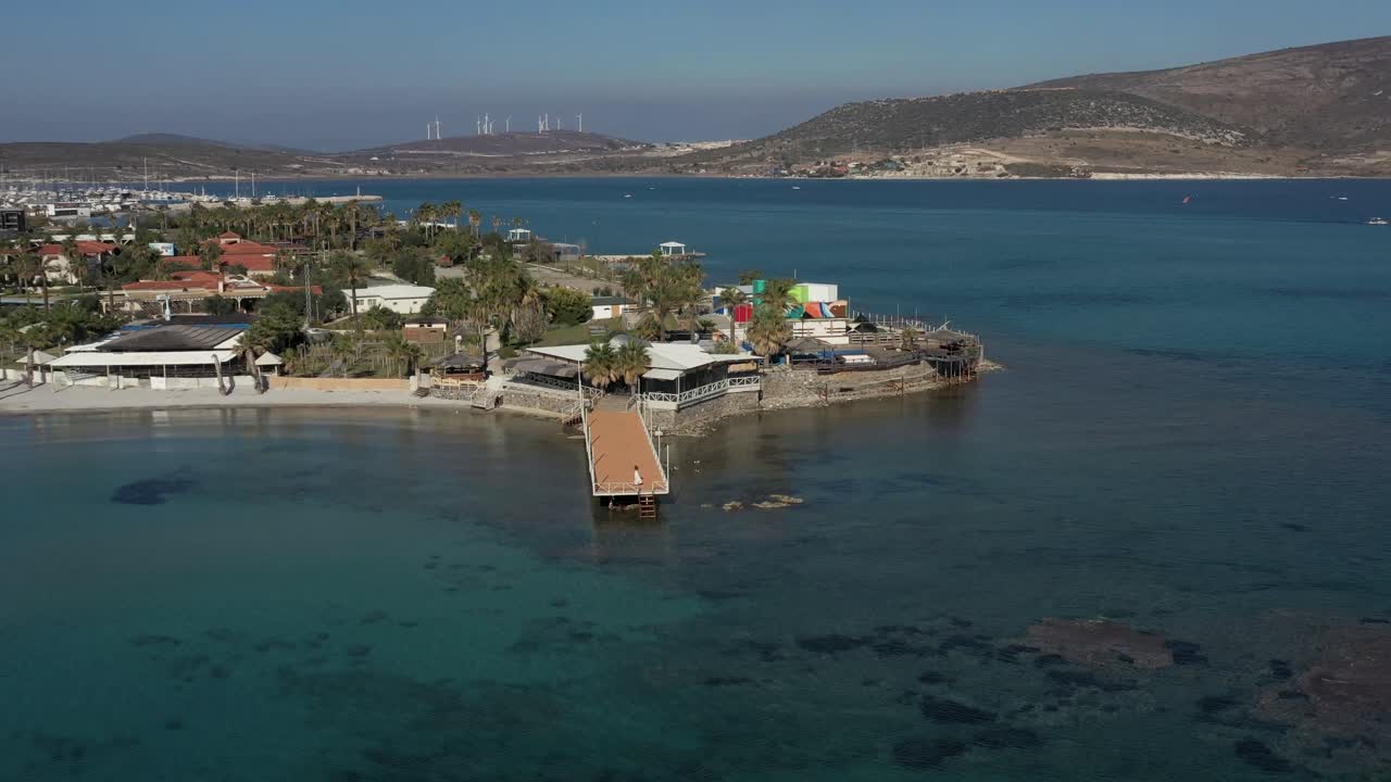 дрон приближается к женщине, грациозно танцующей на пирсе, окруженной спокойным морским пейзажем и горами в гавани во флориде, сша, раскрывая обширные воды и пришвартованные лодки