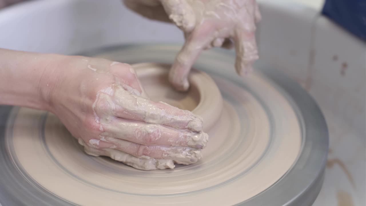 el maestro alfarero le enseña al niño a trabajar con arcilla en la rueda del alfarero.