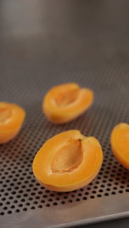 halved apricots on a perforated tray