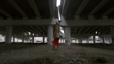 parkourist performing stunts under urban bridge