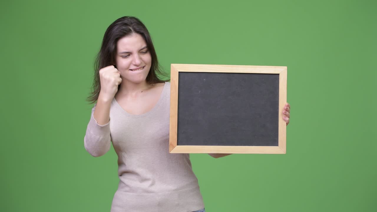 Young happy beautiful woman looking excited while holding blackboard