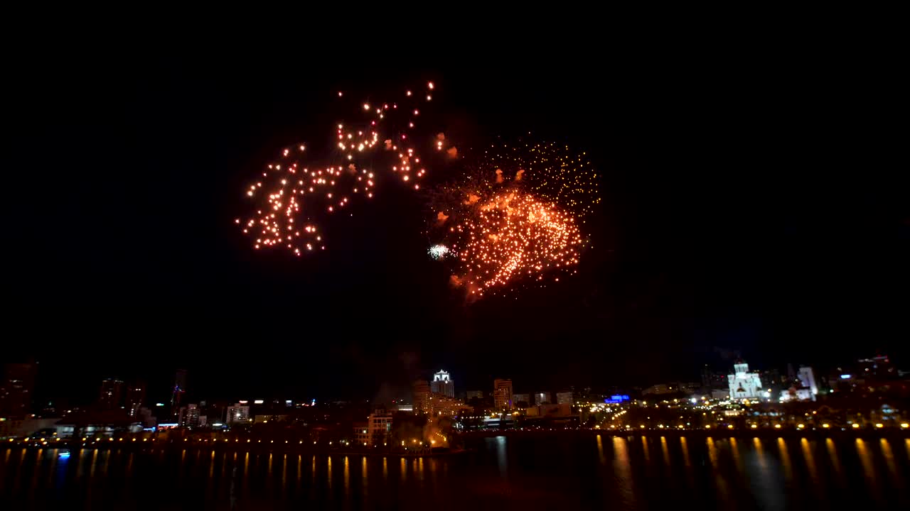 fuegos artificiales sobre una ciudad junto al río por la noche