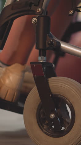 legs of female patient with disability moving in wheelchair in room on blurred background. paralyzed woman in modern mobility device closeup