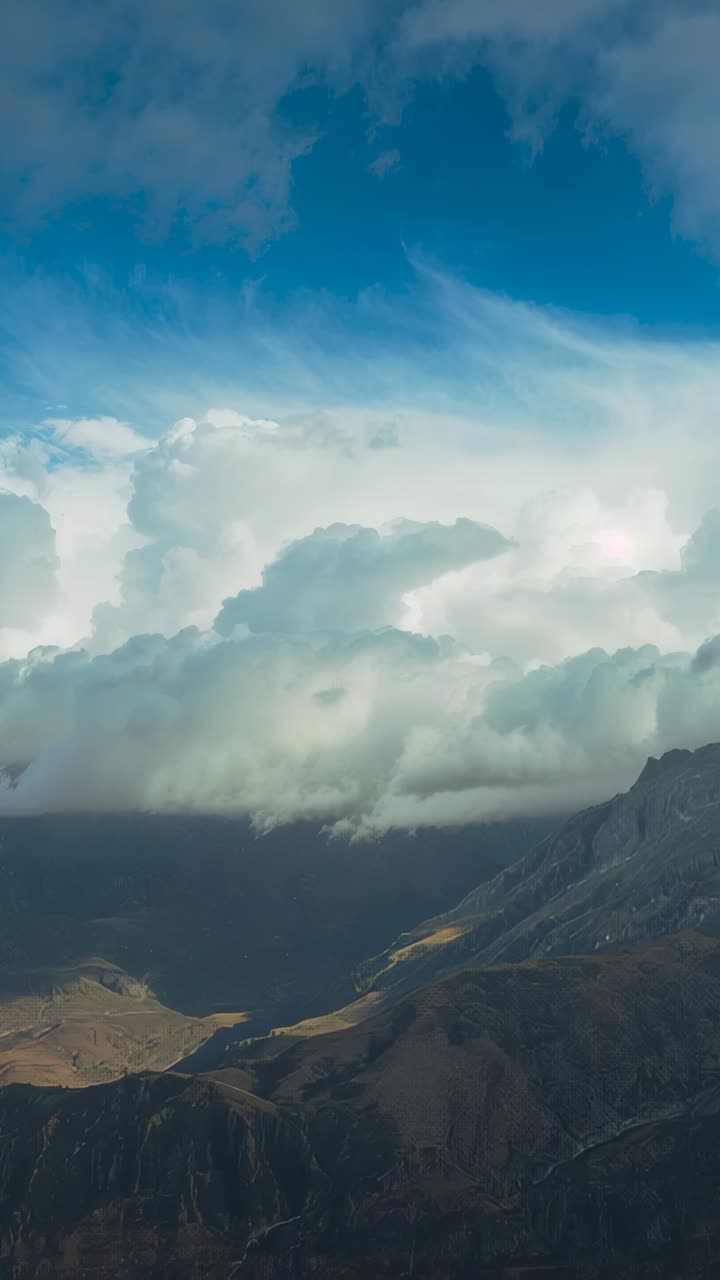 Video verticale: il vento spinge una coltre di nuvole che si sposta su una valle alpina, chiazze di sole che cambiano