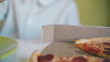 Junge-Im-Hemd-Beißt-Köstliche-Pizza-Am-Tisch,-Nahaufnahme