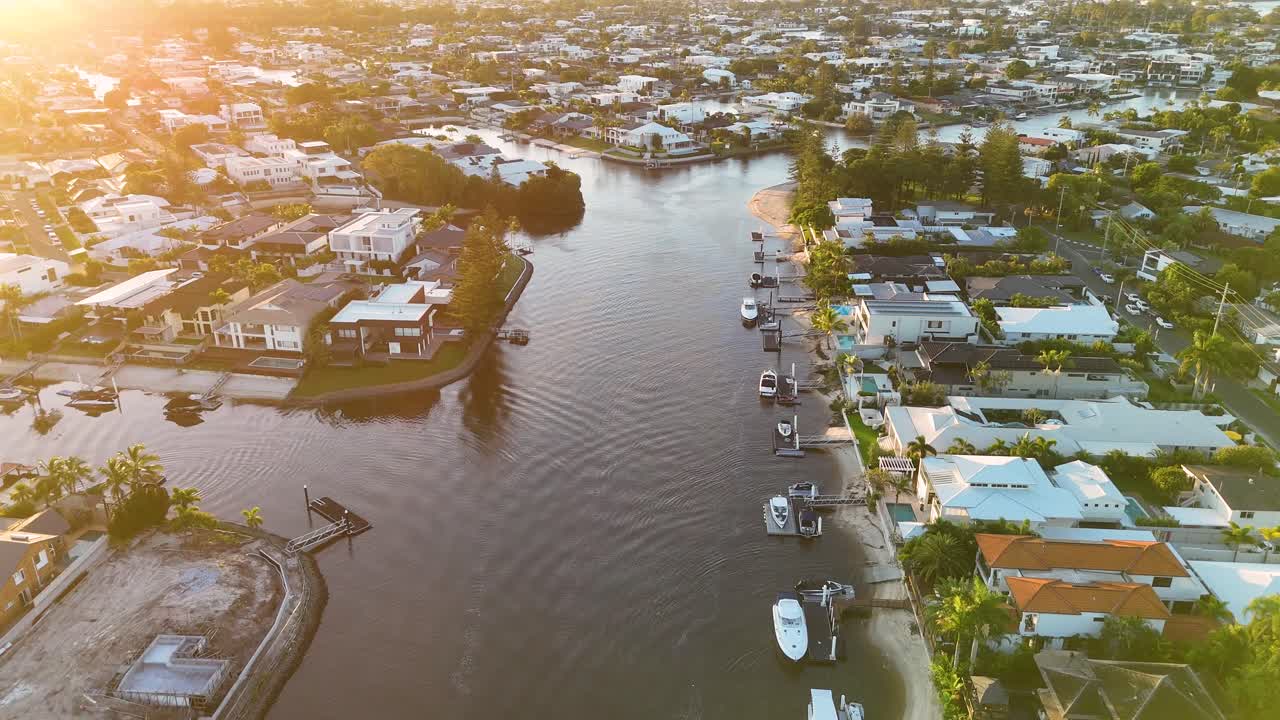 Un drone cattura viste mozzafiato del tramonto sulle lussuose case sui canali della Gold Coast, evidenziando corsi d'acqua sereni e architettura vivace