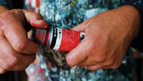 artista pintor abriendo el tubo de pintura roja