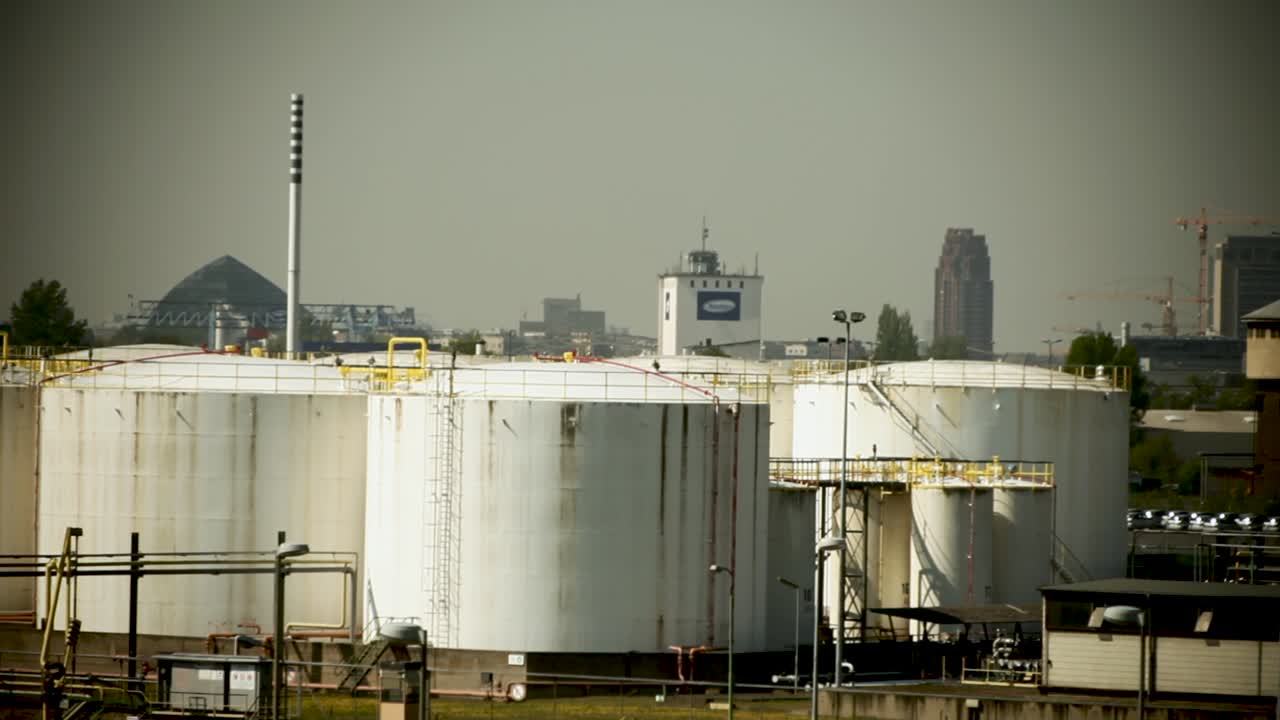 도시 스카이라인을 배경으로 한 산업용 연료 저장 크, 에너지와 도시 산업의 느낌을 전달합니다.