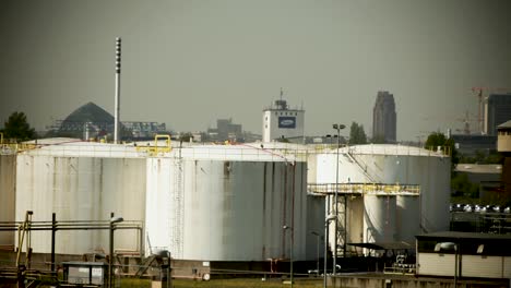 industrial fuel storage tanks with city skyline in the background, conveying a sense of energy and urban industry