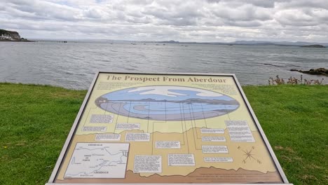 día nublado en la playa de aberdour con un letrero informativo