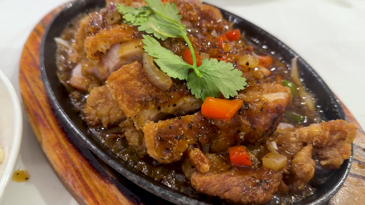 Ayam iris renyah mendesis di atas piring besi cor panas dengan saus bawang putih dan rempah-rempah
