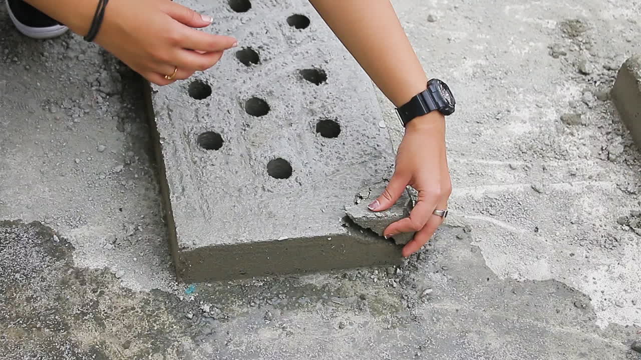 Indian woman inspecting imperfect perforated concrete slab, indicating the product is not meant for use.