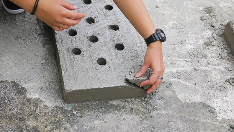 indian woman inspecting imperfect perforated concrete slab, indicating the product is not meant for use.