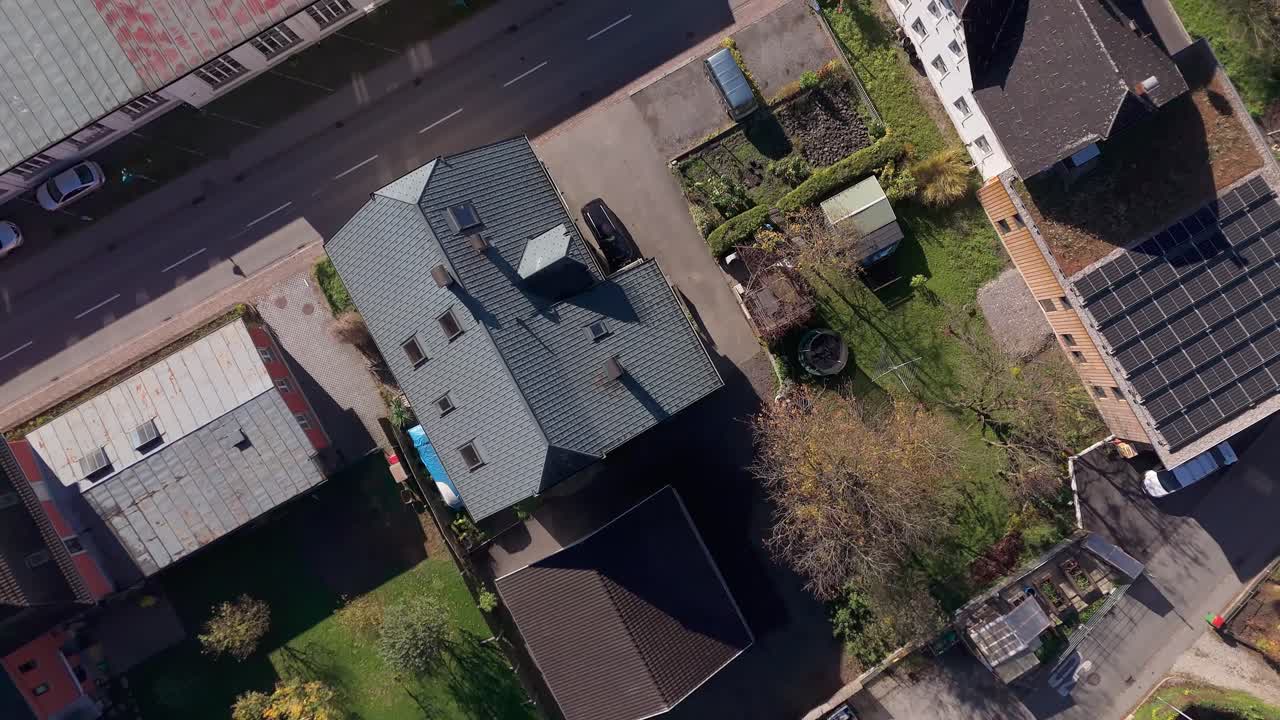 Roofs of townhouses and single family homes with solar panels. Sunny day in fall season. Small town in Austria. Road and streets in quiet city. aerial top down flyover