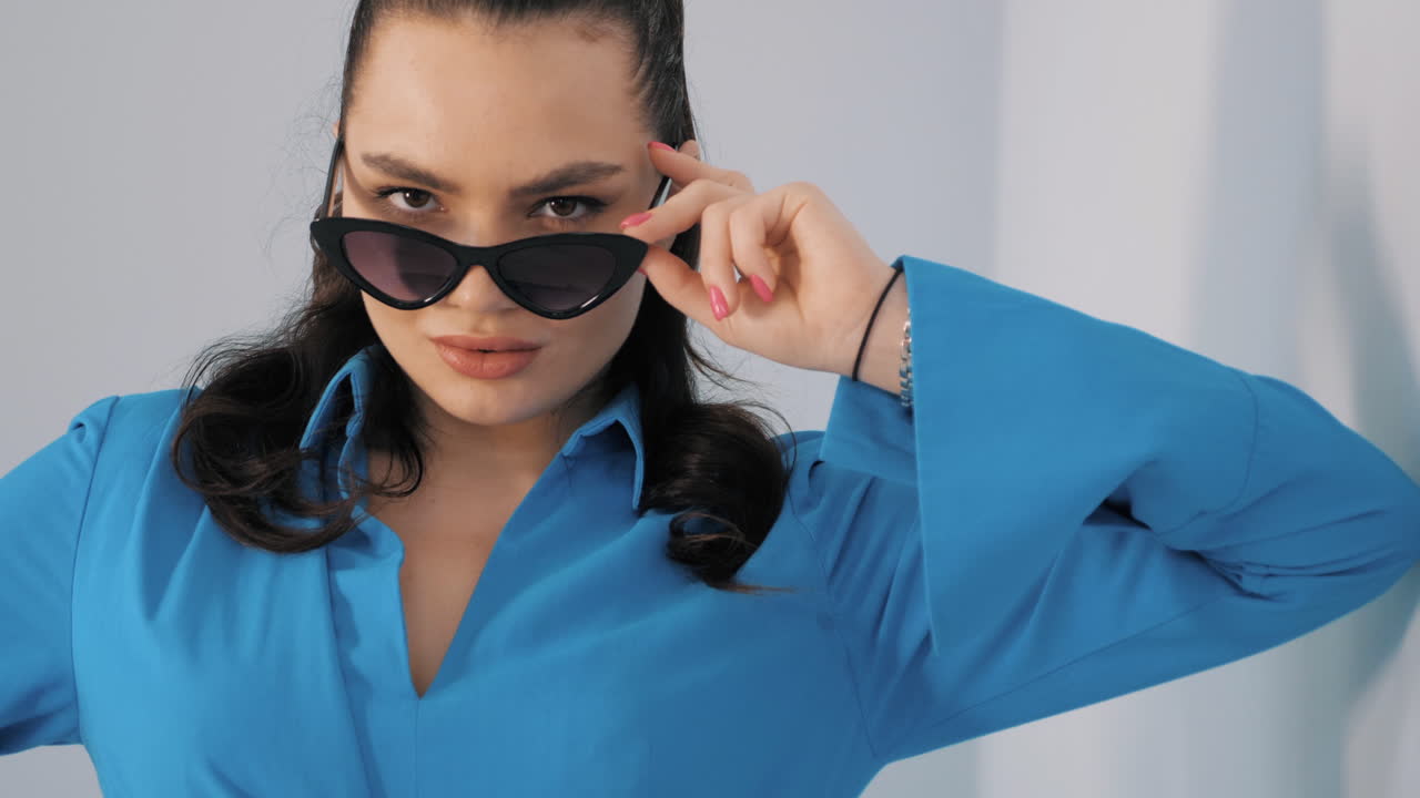 파란 셔츠와 선글라스를 입은 세련된 여성