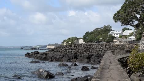 Sendero-A-Lo-Largo-Del-Antiguo-Malecón-Rocoso-De-Una-Playa-Del-Norte-De-Auckland-En-Un-Soleado-Día-De-Primavera-Con-Pocas-Nubes-Cúmulos