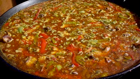 zoom out of a boiling paellón before tossing the rice