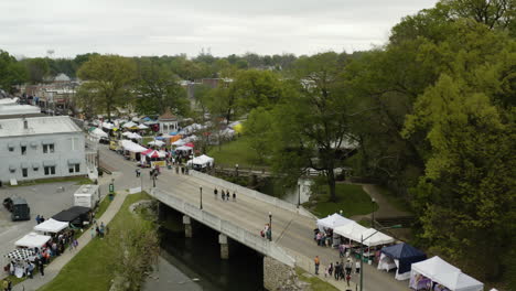 AERIAL---Sager-Creek,-Dogwood-Festival,-Siloam-Springs,-Arkansas,-lowering-shot