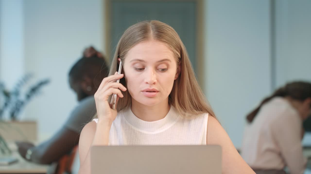 Angry woman shouting in mobile phone at coworking space