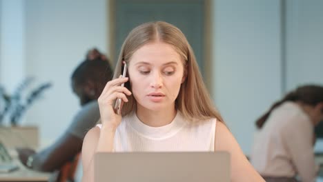 Angry-woman-shouting-in-mobile-phone-at-coworking-space